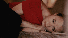 a woman in a red top is laying on a blanket