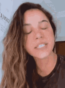 a woman with her eyes closed is wearing a black shirt .