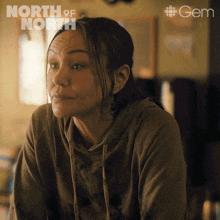 a woman is sitting in front of a sign that says north of north on it