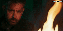 a man in a dark room with a fire in the background and the words pranay varha on the bottom left
