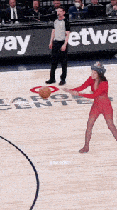 a woman in a red outfit is holding a basketball on a basketball court in front of a sign that says way