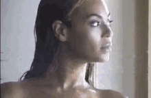 a naked woman with wet hair is standing in a shower .