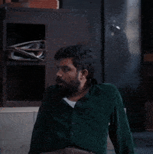 a man with a beard wearing a green shirt looks to his left