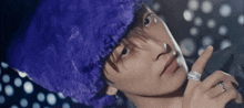 a man wearing a purple fur hat and a ring on his finger
