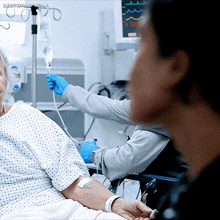 a woman in a hospital bed with a needle in her arm and a monitor behind her that says bestofsuperya