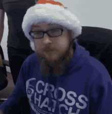 a man wearing glasses and a santa hat is wearing a purple cross hatch sweatshirt
