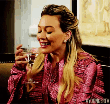 a woman in a pink shirt is drinking a martini while sitting at a table .