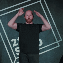 a bald man with a beard is standing in front of a sign that says 21 s