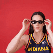 a woman wearing an indiana jersey is adjusting her sunglasses
