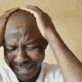a bald man is holding his head in pain while crying .