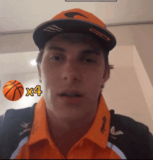 a man wearing an orange shirt and a hat with a basketball on his shirt that says x4