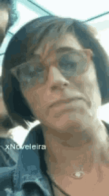 a woman wearing sunglasses and a necklace is looking at the camera .
