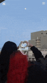 two women with red hair are making a heart shape with soap bubbles .