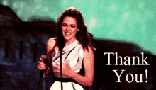 a woman stands in front of a microphone with the words thank you written below her