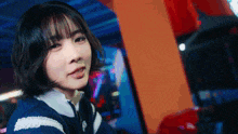 a woman with short hair is sitting in an arcade and looking at the camera