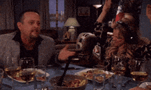 a group of people sitting at a table with plates of food and wine glasses