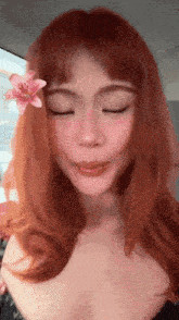 a woman with red hair and a flower in her hair is making a face .