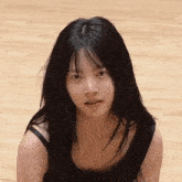 a young woman with long black hair is sitting on a wooden floor