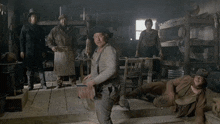 a group of men are standing in a room and one of them is kneeling down