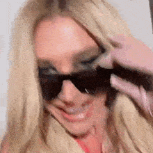 a woman wearing sunglasses is smiling and making a funny face .
