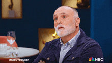 a man sitting at a table with a nbc logo on the bottom