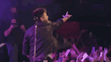 a man is singing into a microphone in front of a crowd of people at a concert .