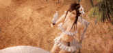 a video game character in a bikini is standing on a beach holding a bottle of water .