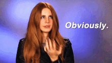 a woman with long red hair is wearing a black jacket and says obviously