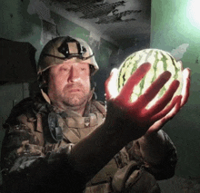 a soldier holds a watermelon in his bloody hands