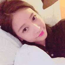 a close up of a woman laying on a bed with a button on her shirt