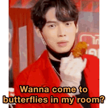 a young man in a red jacket is holding a fried chicken wing and says wanna come to butterflies in my room ?