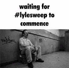 a black and white photo of a man sitting on a crate with the words waiting for #lylesweep to commence