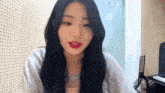 a woman with long black hair and red lips is sitting in front of a piano .