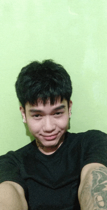 a young man with a tattoo on his arm is smiling for the camera