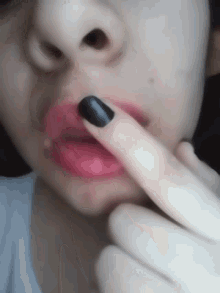 a close up of a woman 's face with black nail polish