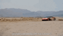 a red sports car is driving through the desert with the words children dropping off the grands .