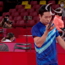 a man in a blue shirt holds a racket in his hand