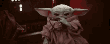 a baby yoda with a stethoscope around his neck is sitting in a dark room .