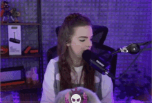 a woman is singing into a shure microphone in a purple room .