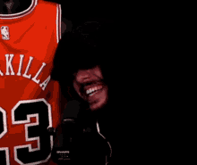 a man is smiling in front of a basketball jersey with the number 23 on it .