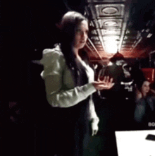 a woman is standing in a dark room with her hands outstretched