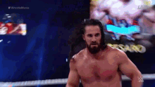 a shirtless wrestler is standing in a wrestling ring .