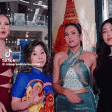 a group of women are posing for a picture in front of a picture of a temple .