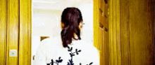 a woman in a ponytail is standing in a doorway looking out a window .