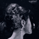 a woman wearing a bun and earrings stands in the rain