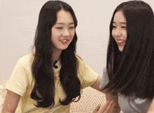 two young girls are sitting next to each other on a bed .