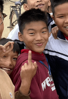 a boy wearing a sweatshirt with the word we on it giving the middle finger