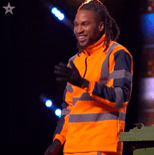 a man with dreadlocks is wearing an orange safety vest