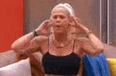 a woman is sitting on a couch with her hands on her ears .