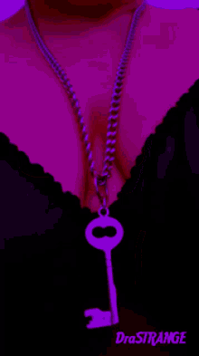 a woman is wearing a necklace with a key hanging from it and the word drastrange is above her